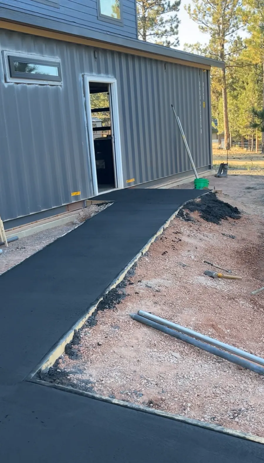 New concrete walkway curing beside a metal-sided building