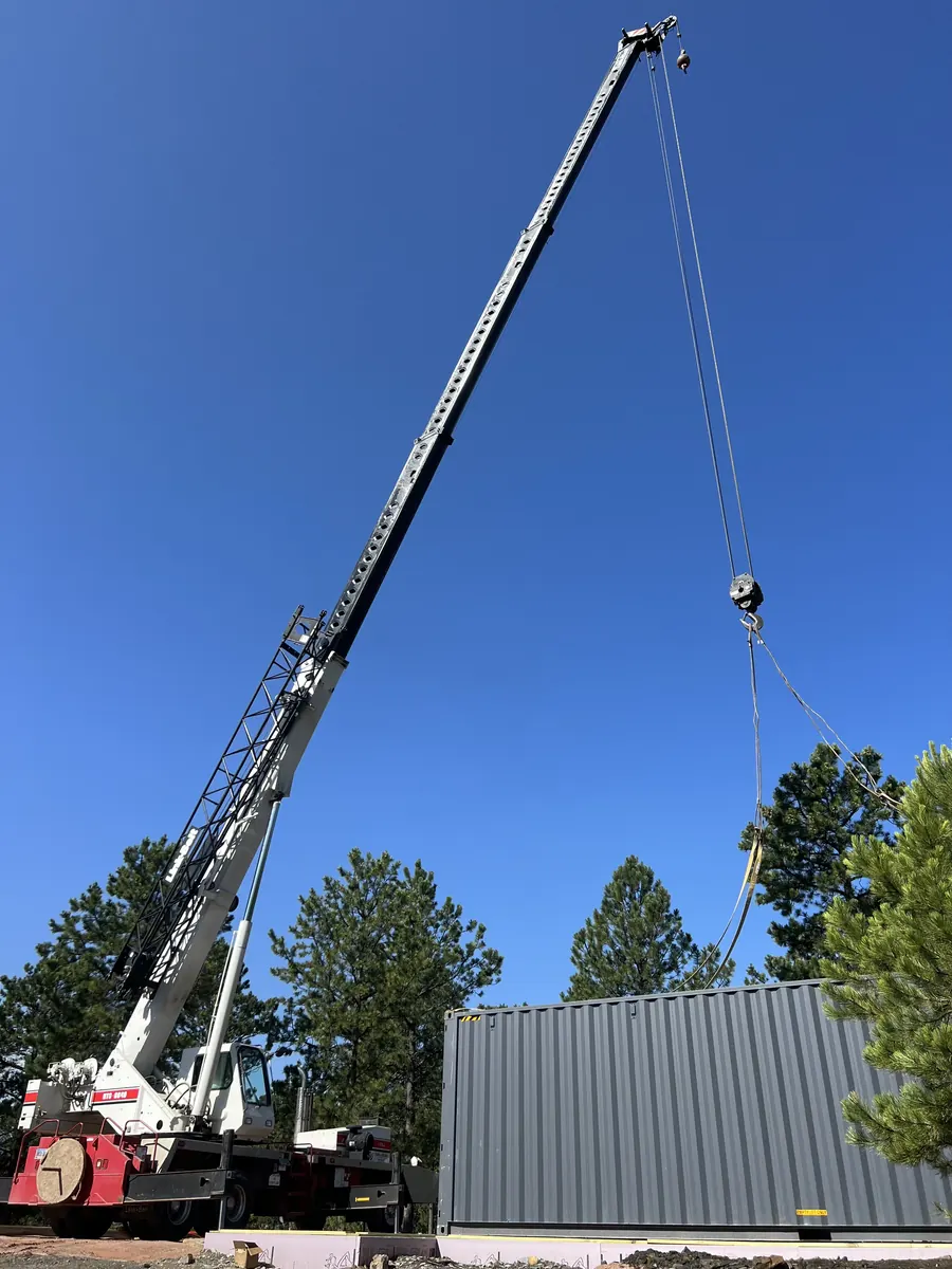 Crane setting a container on a prepared Black Hills site